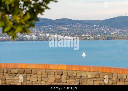 Ein Segelschiff auf dem Balaton in der Herbstsonne mit Balatonfüred im Hintergrund Stockfoto