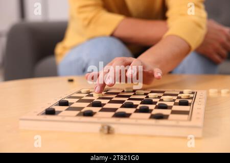 Frau, die Schachfiguren am Holztisch spielt, Nahaufnahme Stockfoto