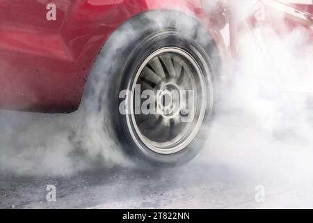 Ziehen Sie den brennenden Reifen des Rennwagens an der Startlinie auf der Rennstrecke Stockfoto