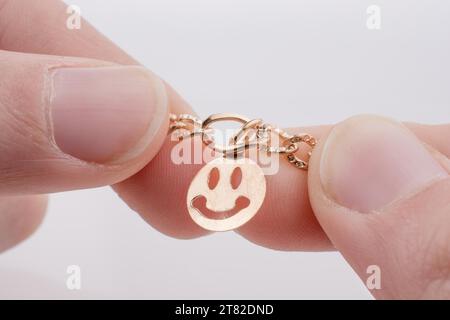 Goldene Farbe Smileys aufgereiht an einer Kette in der hand Stockfoto