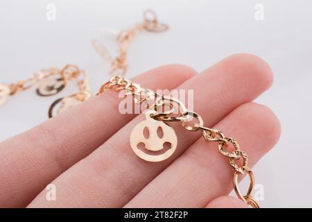 Goldene Farbe Smileys aufgereiht an einer Kette in der hand Stockfoto