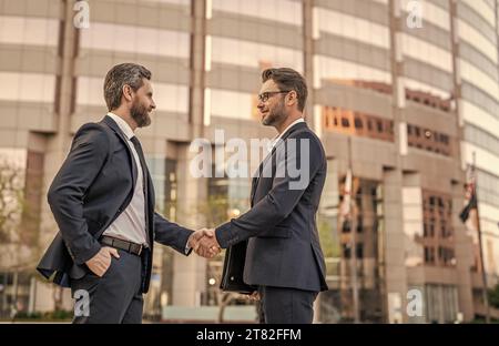 Zwei Geschäftsleute kümmern sich um Handschlag im Freien, Kopierraum. Zwei Geschäftsmänner im Anzug Stockfoto