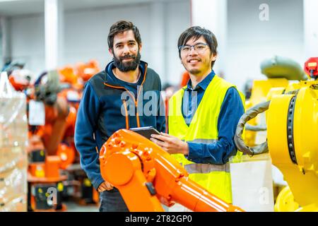 Porträt zweier junger multiethnischer Ingenieure in einer industriellen Roboterindustrie, die die Kamera anschauen und lächeln Stockfoto