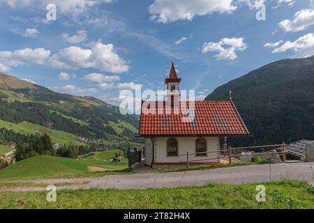 Rosenkranzkapelle, Almdorf Gemais, Außenansicht, Hanglage, Turm, alpine Bergwelt, Nadelwald, blauer Himmel, Tux, Tuxtal Stockfoto