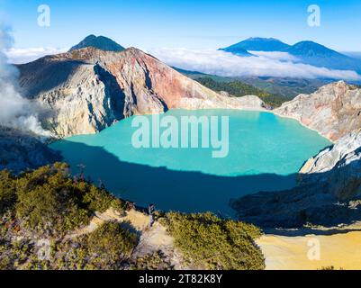 Aus der Vogelperspektive auf die Felsenklippe am Kawah Ijen Vulkan mit türkisfarbenem Schwefelwassersee bei Sonnenaufgang. Fantastischer Blick auf die Naturlandschaft in Ost-Java, Indonesien. Natu Stockfoto