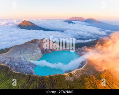 Aus der Vogelperspektive auf die Felsenklippe am Kawah Ijen Vulkan mit türkisfarbenem Schwefelwassersee bei Sonnenaufgang. Fantastischer Blick auf die Naturlandschaft in Ost-Java, Indonesien. Natu Stockfoto