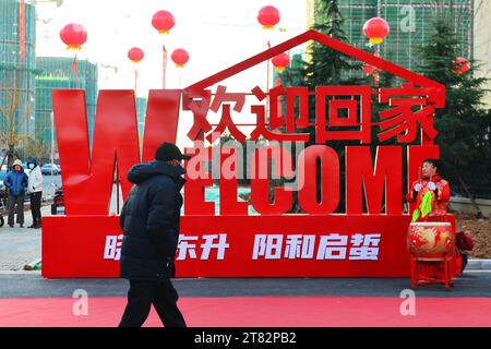 QINGDAO, CHINA - 18. NOVEMBER 2023 - Ein Bewohner geht an einer Willkommenstafel an der Wohnsiedlung der Xiaoyang Gemeinde in Qingdao vorbei. Stockfoto