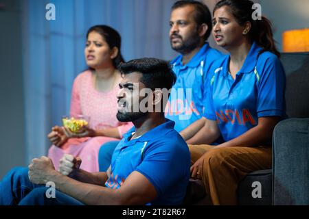 Angespannte ältere Eltern mittleren Alters mit Geschwistern, die Live-Cricket-Sportspiele mit indischen T-Shirts zu Hause auf dem Sofa anschauen - Unterhaltungskonzept Stockfoto