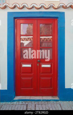 Winzige Tür mit lebhaften Farben im Vila Nova de Milfontes Haus. Kleine malerische Stadt an der Küste von Alentejo, Portugal Stockfoto