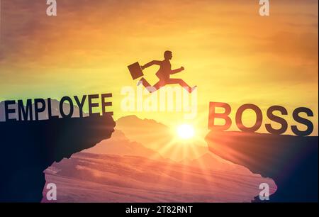 Karrieresprung. Silhouette eines Mannes, der von der Klippe des Mitarbeiters zur Klippe des Managers vor dem Hintergrund des Sonnenuntergangs springt. Motivation für Karriereentwicklung. Stockfoto