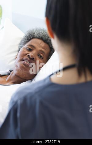 Diverse Ärztin im Gespräch mit älteren Patientinnen im Krankenhauszimmer Stockfoto
