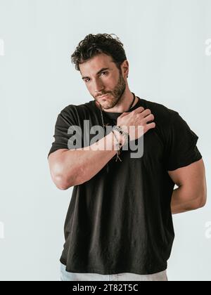 Ein Mann in einem schwarzen Hemd posiert für ein Bild, auf weißem Hintergrund Stockfoto