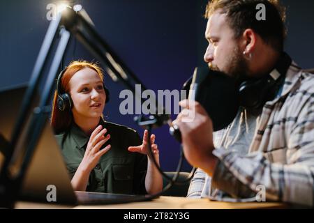 Mann, der sich mit Frau im Internet mit professionellem Mikrofon und Audiomikrofon unterhält. Online-Radiosender hosten Podcast in Stockfoto