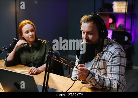 Zwei radio Hosts in Kopfhörer lachen während der Aufnahme Podcast im Studio zusammen Stockfoto