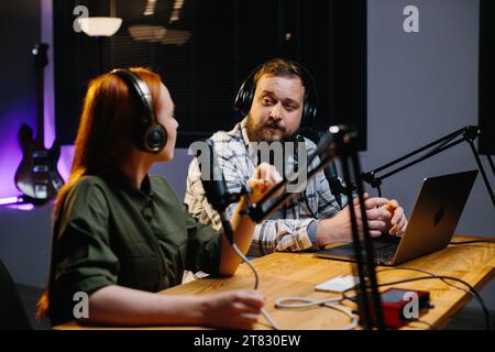 Zwei radio Hosts in Kopfhörer lachen während der Aufnahme Podcast im Studio zusammen Stockfoto