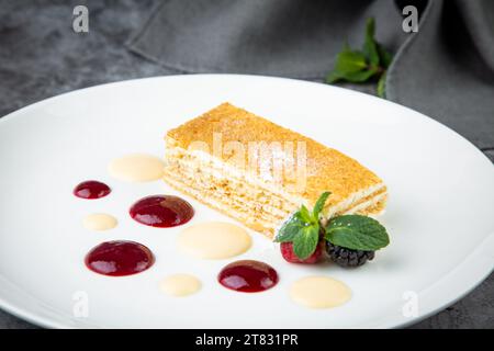Weißer Biskuitkuchen mit Tropfen Sirup, Minze und Waldbeeren auf einer runden Tellerseite Stockfoto