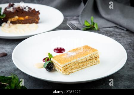 Weißer Biskuitkuchen mit Tropfen Sirup, Minze und Waldbeeren auf einer runden Tellerseite Stockfoto