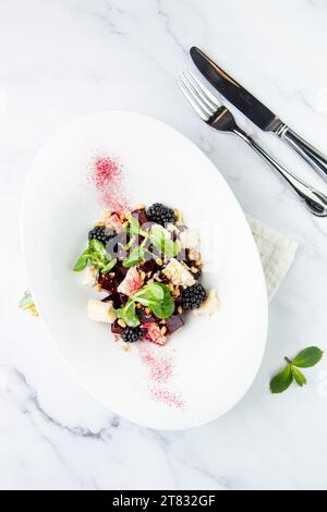 Salat aus Brombeeren, Rüben, Samen und Käse, Blick von oben auf einem weißen Teller Stockfoto