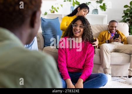 Glückliche Teenager-Freunde, die ihr Smartphone nutzen und zu Hause im Kreis sprechen Stockfoto