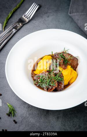 Kartoffelpüree mit Fleisch, Soße und Kräutern in einer tiefen Seitenansicht des Tellers Stockfoto