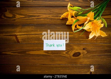 Strauß wunderschöner gelber Lilien auf einem dunklen Holztisch Stockfoto