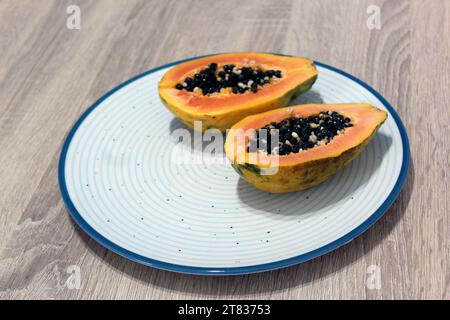 Zwei Scheiben reifer Papaya auf einem blauen Teller mit hölzernem Hintergrund Stockfoto