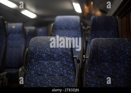 Sitzplätze für Busse. Leere Sitze beim Transport. Businnenraum ohne Personen. Öffentliche Verkehrsmittel im Inneren. Weiche blaue Sitze für Passagiere. Stockfoto