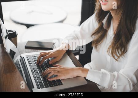 Fröhlicher, schöner Freiberufler, der die Tastatur auf dem Laptop tippt, um eine Blog-Webseite zu schreiben Stockfoto