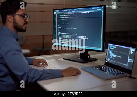 Softwareentwickler, der spät am Computer im dunklen Büro arbeitet. Stockfoto