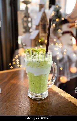 Kiwi-Saft-Milchshake-Smoothie im Glas auf Holztisch und heller Bokeh-Hintergrund Stockfoto