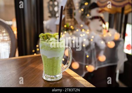 Kiwi-Saft-Milchshake-Smoothie im Glas auf Holztisch und heller Bokeh-Hintergrund Stockfoto