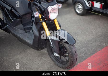 Moto-Elektrofahrzeuge sind in einer Reihe. Verleih von Elektrofahrrädern. Scheinwerfer an Fahrzeugen mit zwei Rädern. Motorradverkauf. Massenparkplätze für Fahrzeuge. Modern urban Stockfoto