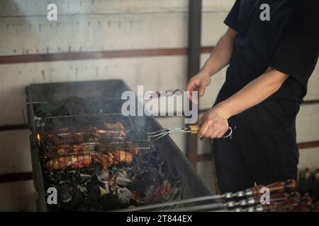 Mann, der Fleisch frittiert. Mann kocht Rindfleisch. Herzhafte Mahlzeiten. Kochen von Fleisch über Holzkohle. Stockfoto