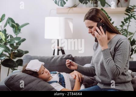 Traurige kranke Jugendliche Mädchen, die auf dem Sofa liegen, fühlen Fieber sich Erkältungsgrippe Grippe. Die ängstliche Mutter, die Telefon an Ohr hält, ruft danach den Doc-Familientherapeuten an Stockfoto