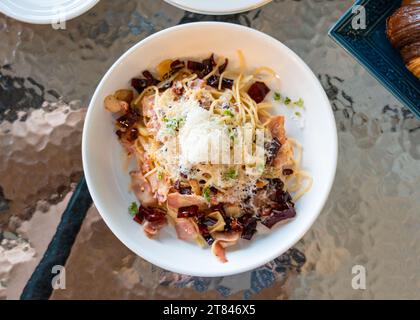 Gebratene Spaghetti, getrocknete Chili, Speck und Kräuter in einem weißen Teller im italienischen Restaurant Stockfoto