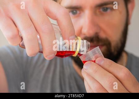 Nahaufnahme einer Person, die Hustensirup eingießt. Stockfoto