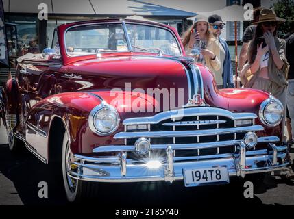 Mount Maunganui Neuseeland - 12. November 2023; Sternenfunkeln des Chromgrills und Stoßfänger des roten Vintage Pontiac, während die Leute im Hintergrund mitnehmen Stockfoto