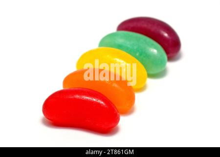 Nahaufnahme einer Reihe von bunten Jelly Beans in einem Regenbogenmuster von Rot, Orange, Gelb, Grün, Violett, vor weißem Hintergrund aufgenommen. Stockfoto