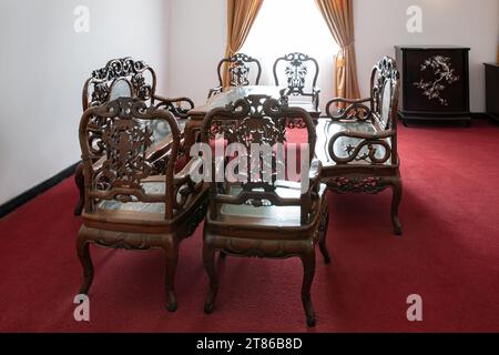 Ho Chi Minh City, Vietnam, 25. März 2023: Schöne antike Holzmöbel (Tisch und Stühle) im Wohnzimmer mit rotem Teppich Stockfoto