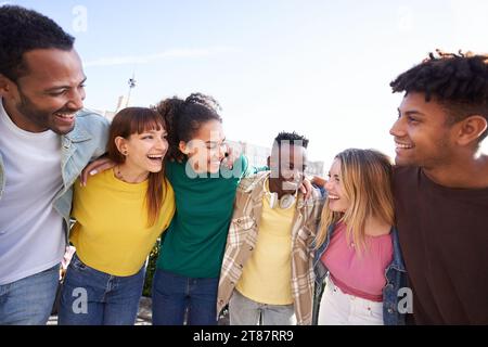 Multirassische junge Leute, die sich im Freien umarmen, verschiedene Studenten und Freunde, die glücklich lachen. Stockfoto