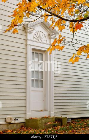 Eingang im Kolonialstil, eingerahmt von lebhaftem Herbstlaub Stockfoto