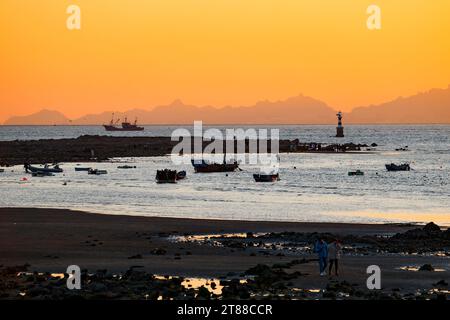 QINGDAO, CHINA - 18. NOVEMBER 2023 - Fischerboote segeln bei Sonnenuntergang an der Küste der Insel Gujia im New Areal der Westküste von Qingdao, Shandong Prov Stockfoto