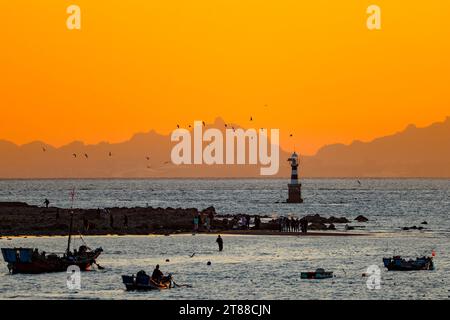 QINGDAO, CHINA - 18. NOVEMBER 2023 - Fischerboote segeln bei Sonnenuntergang an der Küste der Insel Gujia im New Areal der Westküste von Qingdao, Shandong Prov Stockfoto