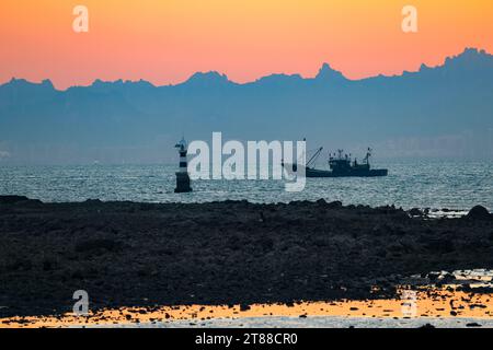 QINGDAO, CHINA - 18. NOVEMBER 2023 - Fischerboote segeln bei Sonnenuntergang an der Küste der Insel Gujia im New Areal der Westküste von Qingdao, Shandong Prov Stockfoto