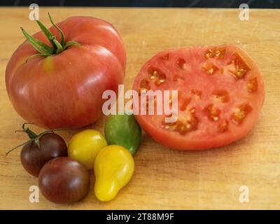 Frische Produkte, farbenfrohe saftige rote gelbe und grüne Tomaten, eine in Hälften geschnitten mit Fleisch und Samen, die in einem australischen Gemüsegarten angebaut werden Stockfoto