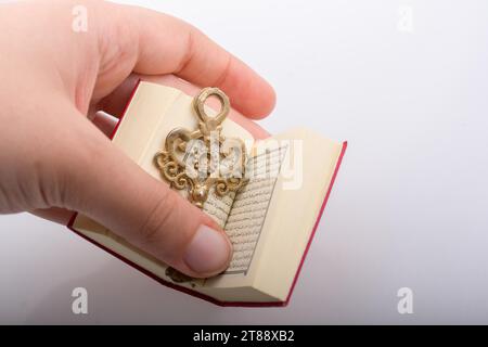 Hand mit Schlüssel und islamischen heiligen Buch Koran in Mini Größe Stockfoto