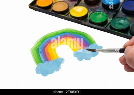 Das Kind zeichnet einen Regenbogen mit Farben Stockfoto