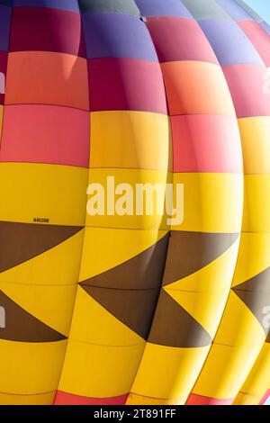 Detail eines aufblasbaren Heißluftballons mit Chevron-Designs und violetten und orangen Farbtafeln. Stockfoto