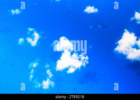 Geschwollene weiße Wolken ziehen über einen tiefen blauen Ozean, ihre Schatten fallen auf die Wellen darunter. Hochwertige Fotos Stockfoto