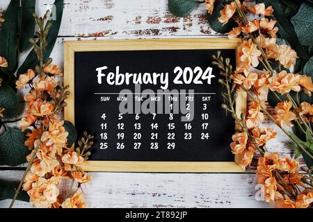 Monatskalender Februar 2024 mit Blumenstrauß Dekoration auf hölzernem Hintergrund Stockfoto